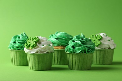 Photo of St. Patrick's day party. Tasty festively decorated cupcakes on green background