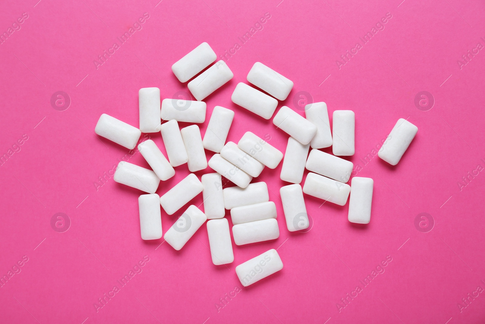 Photo of Tasty white chewing gums on pink background, flat lay