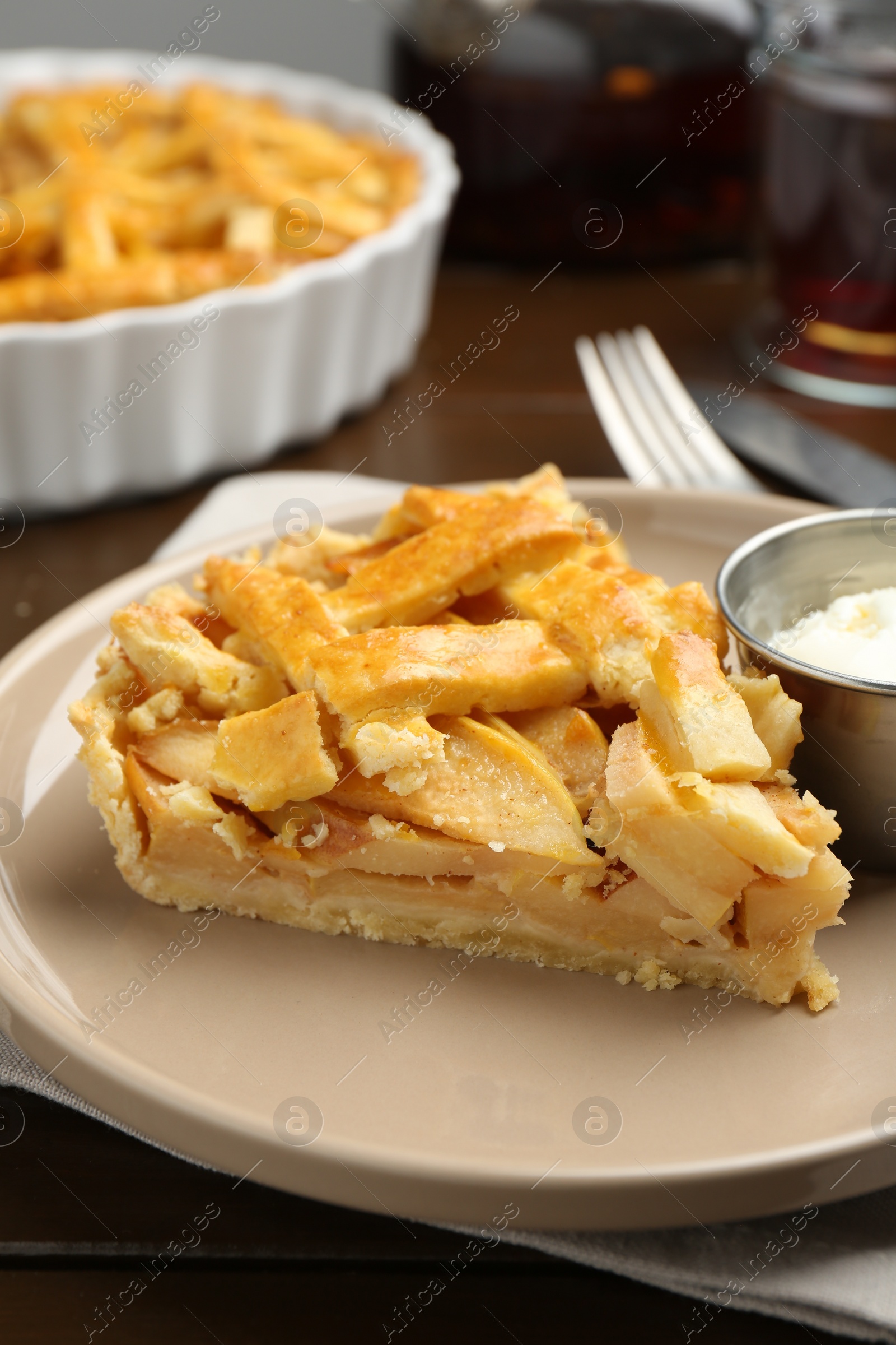 Photo of Piece of tasty homemade quince pie with ice cream on wooden table, closeup