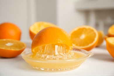Photo of Squeezer and cut fresh oranges on white table, closeup
