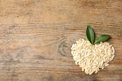 Photo of Heart made of raw cucumber seeds and space for text on wooden background, top view. Vegetable planting