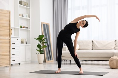 Photo of Girl stretching on yoga mat at home. Janu Sirsasana pose variation