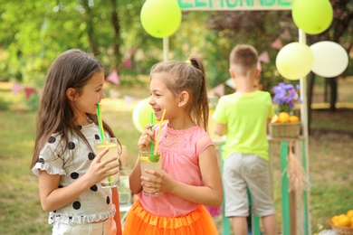 Photo of Little girls with natural lemonade in park