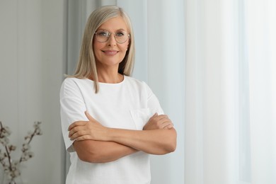 Photo of Portrait of beautiful middle aged woman in eyeglasses indoors, space for text
