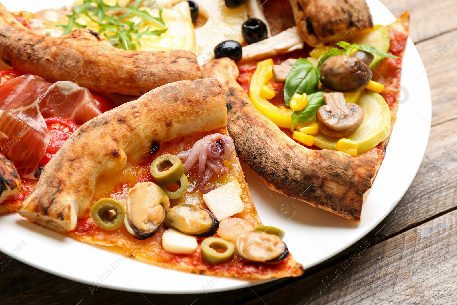 Photo of Slices of different pizzas on wooden table, closeup