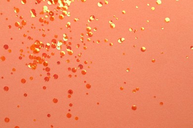 Photo of Shiny bright glitter on coral background, flat lay