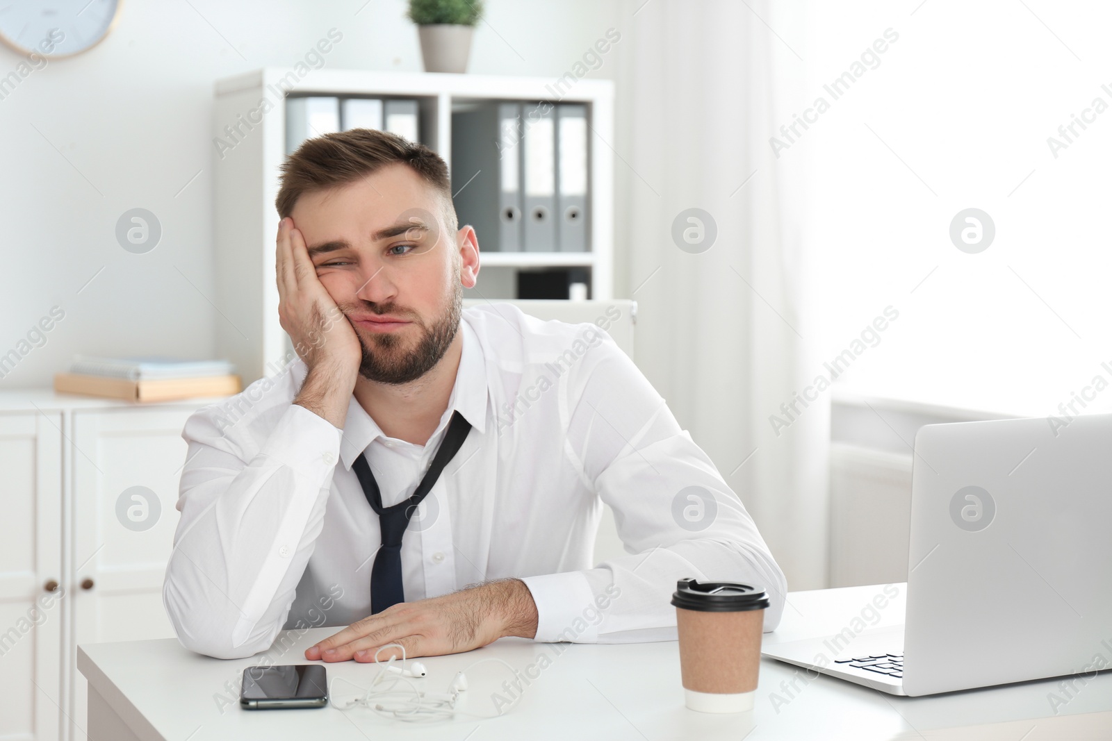 Photo of Lazy young man wasting time at table in office