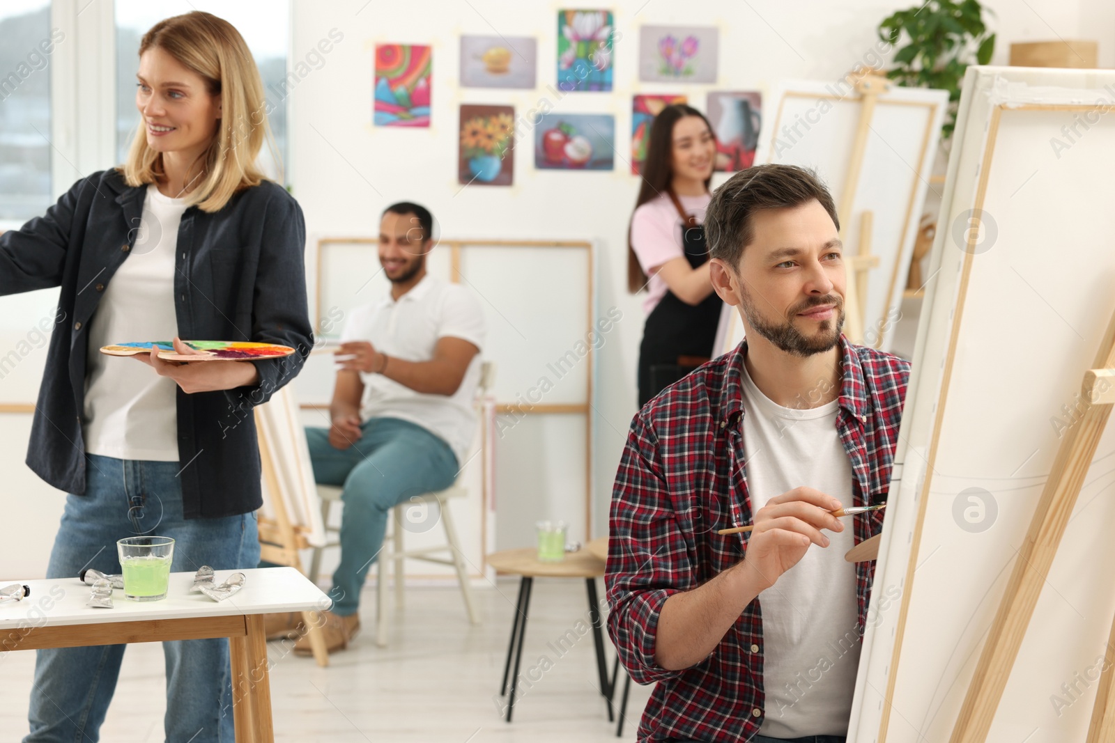 Photo of Group of students attending painting class in studio. Creative hobby