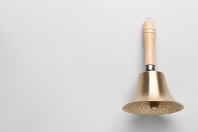 Photo of Golden school bell with wooden handle on grey background, top view. Space for text