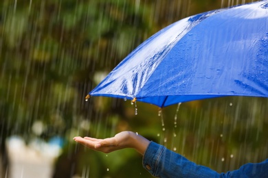 Photo of Woman with bright umbrella under rain on street, closeup