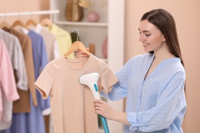 Photo of Woman steaming shirt on hanger at home