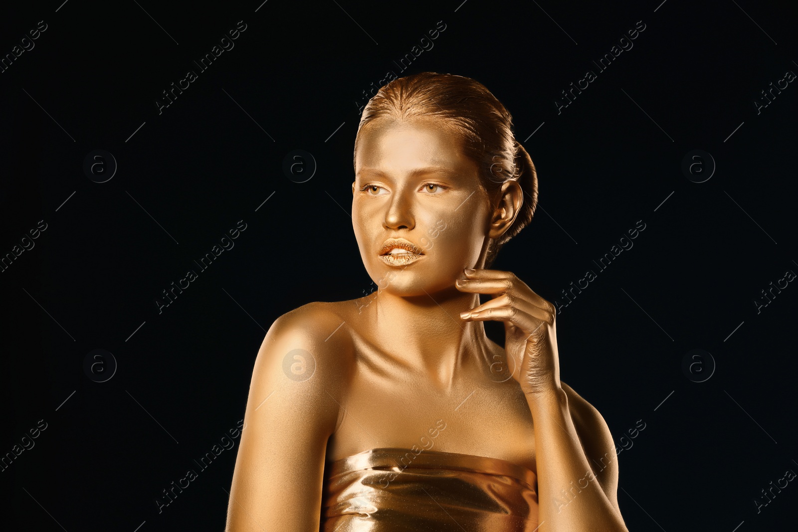 Photo of Portrait of beautiful lady with gold paint on skin against black background