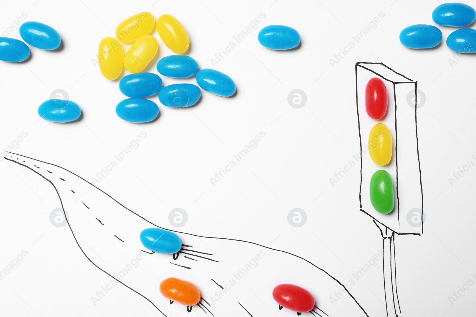 Photo of Colorful jelly candies arranged as traffic light and road with cars on white background, top view