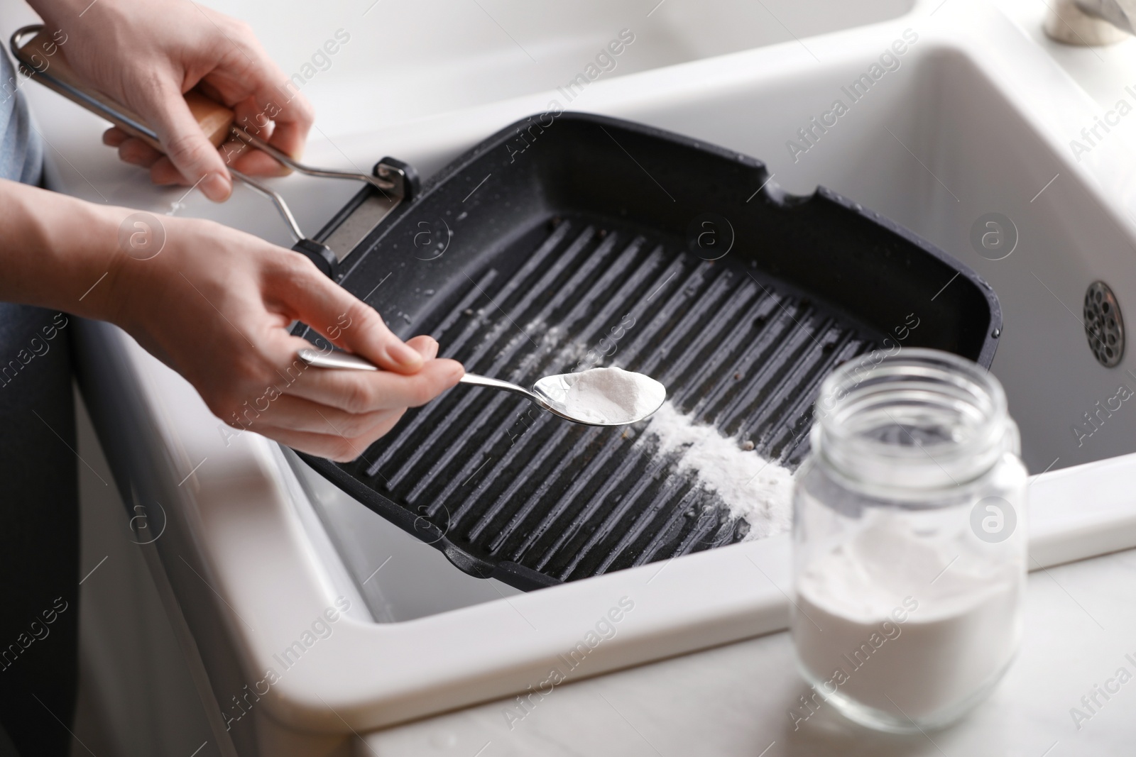 Photo of Woman using baking soda to grill pan indoors, closeup