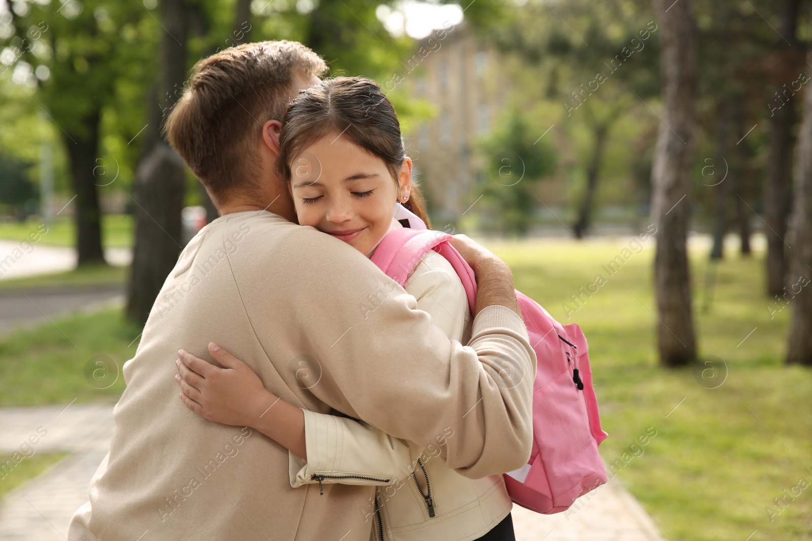 Photo of Father hugging his little daughter before school outdoors