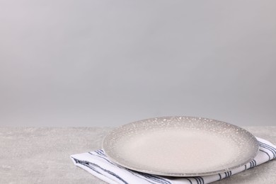 Photo of Empty ceramic plate on gray table against light background, space for text