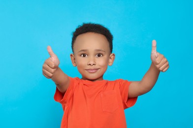 Photo of African-American boy showing thumbs up on turquoise background