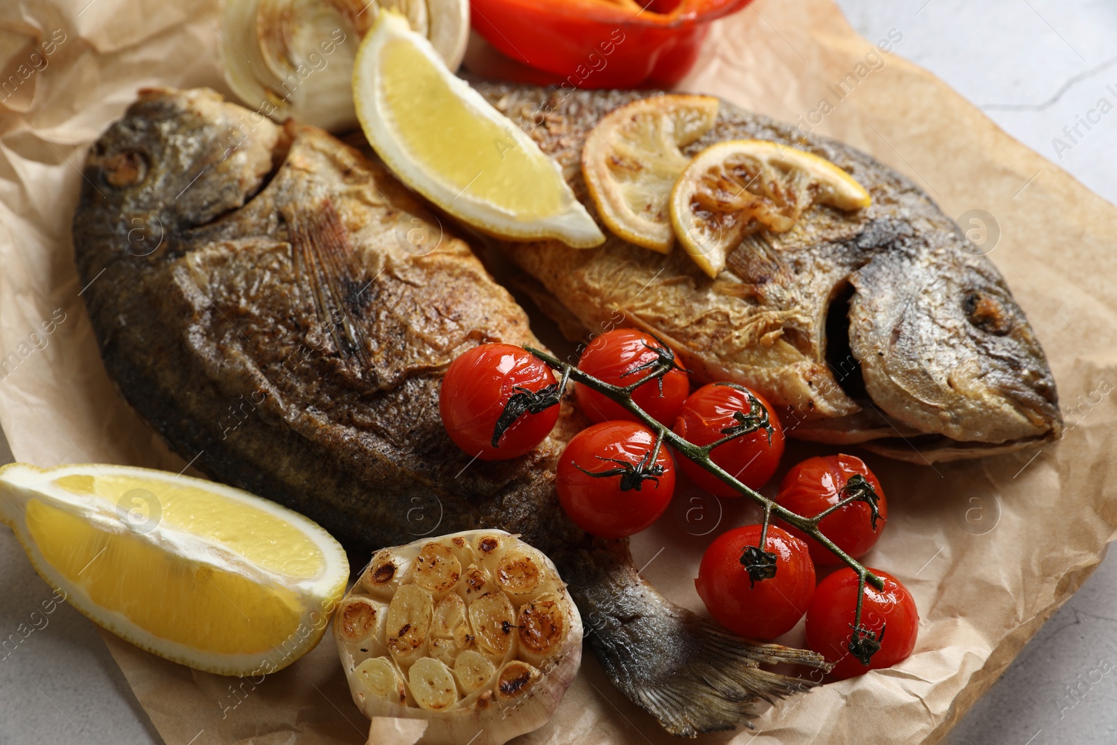 Photo of Delicious dorado fish with vegetables served on table, closeup