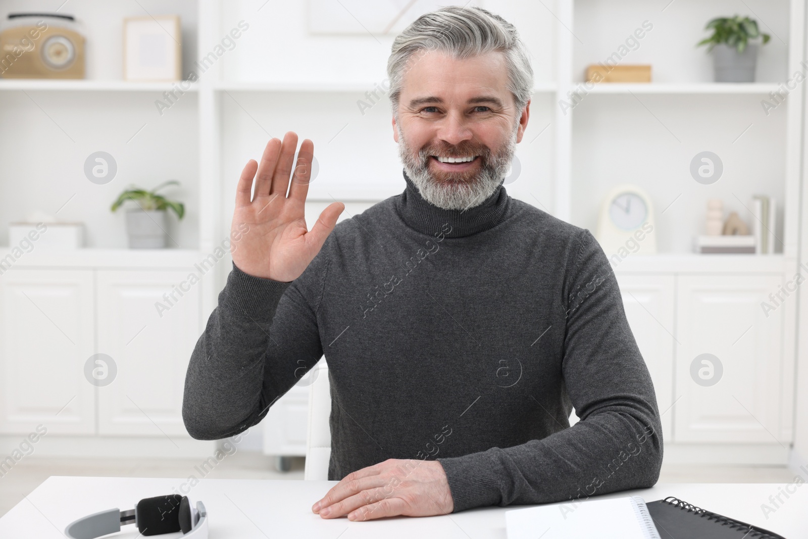 Photo of Man waving hello during video chat at home, view from webcam