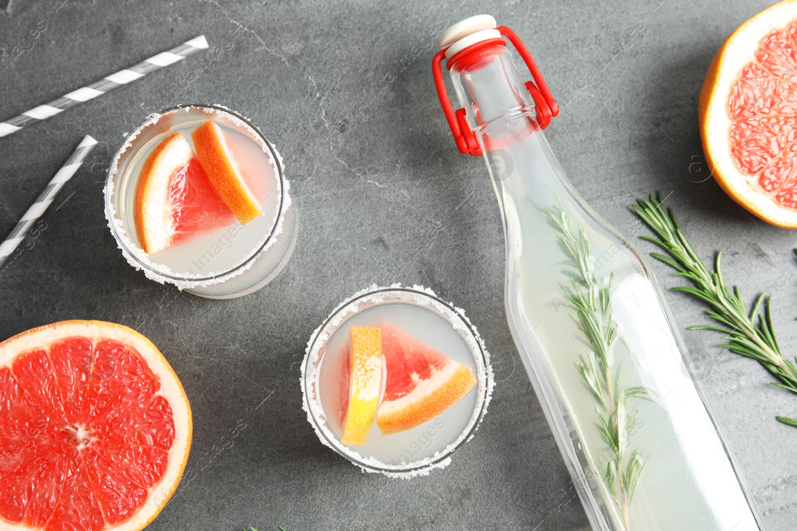 Photo of Flat lay composition with cocktails, grapefruits and bottle on grey table