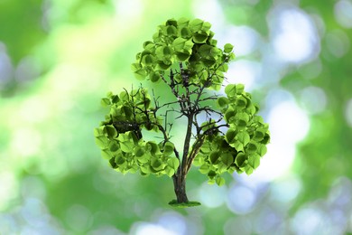 Image of Tree with green leaves in shape of recycling symbol on blurred background. Bokeh effect