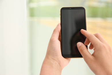 Woman working with modern smartphone indoors, closeup. Space for design