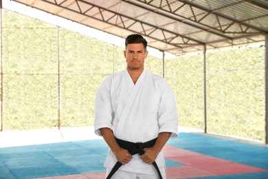Photo of Karate coach wearing kimono and black belt at outdoor gym