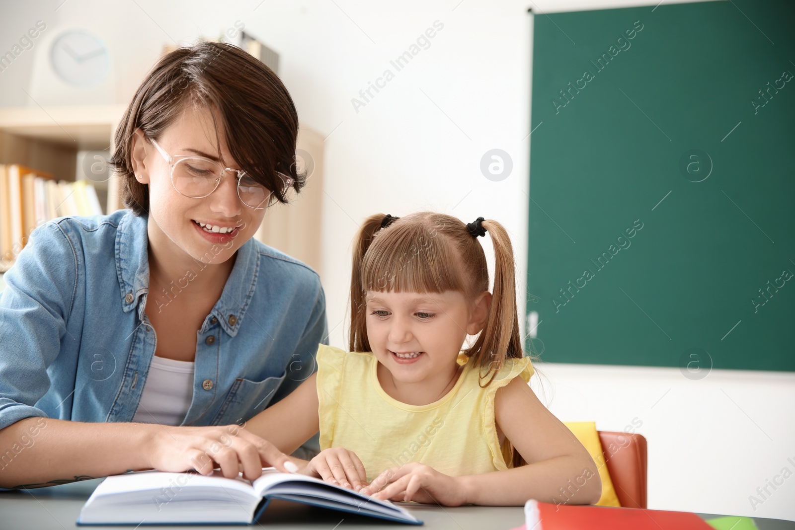 Photo of Female teacher helping child with assignment at school