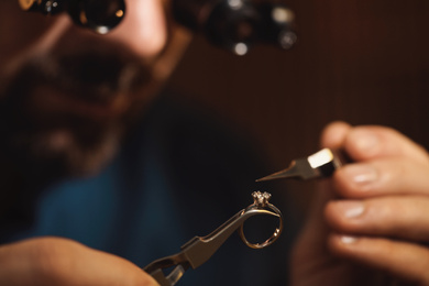 Photo of Jeweler working with ring on blurred background, closeup