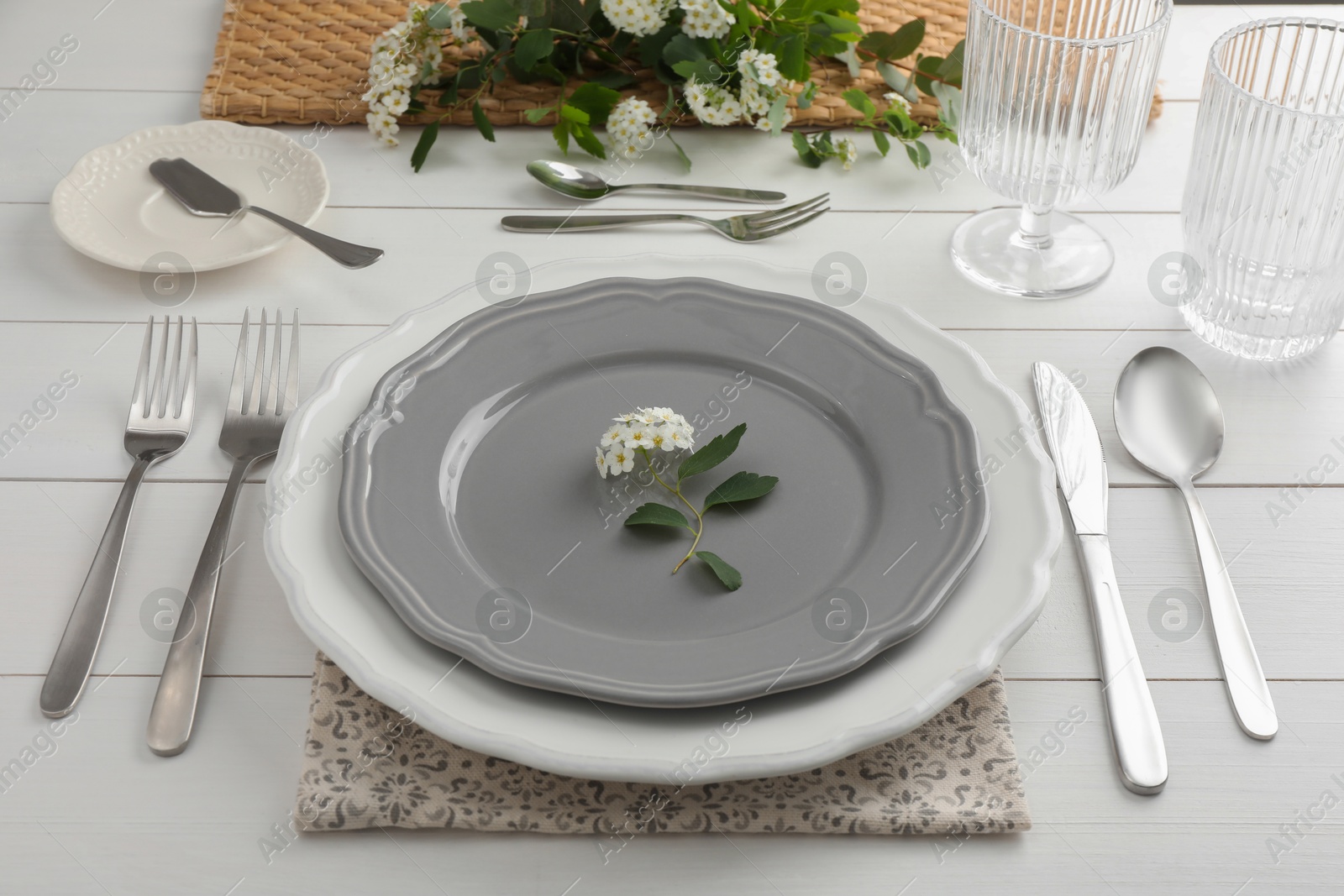 Photo of Stylish setting with cutlery, glasses and plates on white wooden table