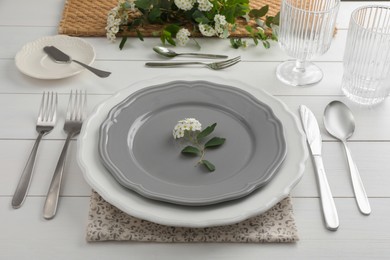Photo of Stylish setting with cutlery, glasses and plates on white wooden table