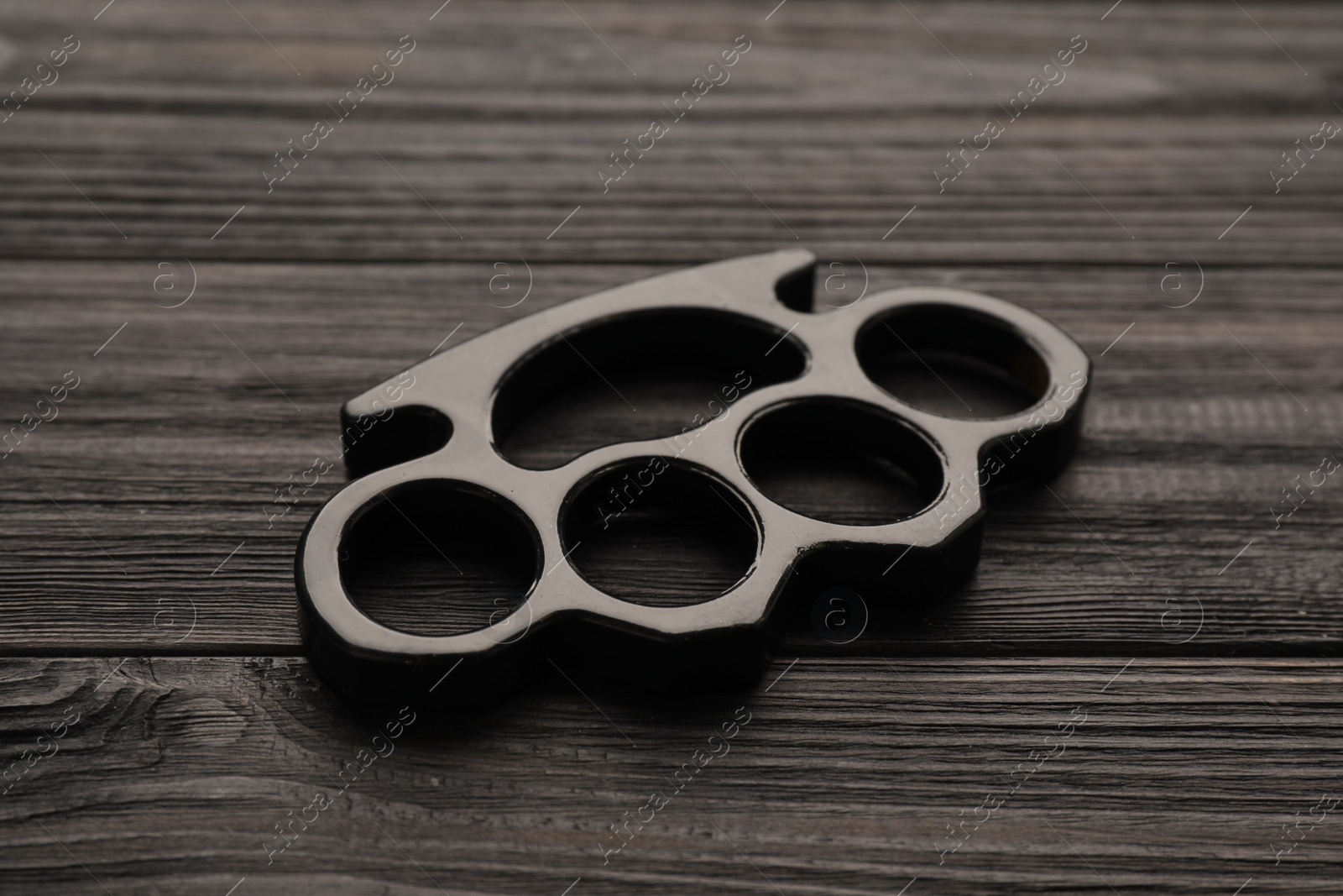 Photo of Brass knuckles on black wooden background, closeup