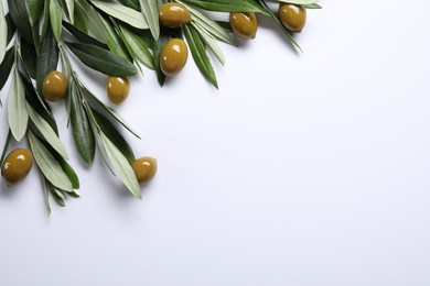 Photo of Fresh green olives and leaves on white background, flat lay. Space for text