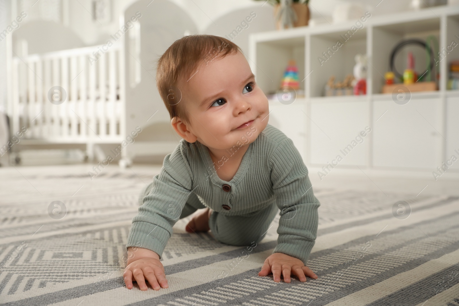 Photo of Cute baby crawling on floor at home