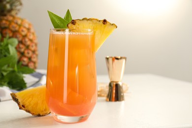 Tasty pineapple cocktail in glass and fresh fruit on white table. Space for text