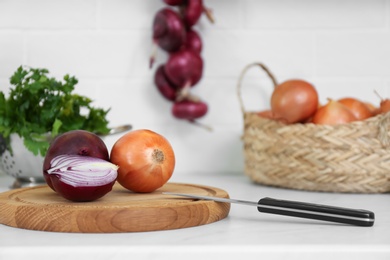 Photo of Fresh cut and whole onions on countertop in modern kitchen, closeup