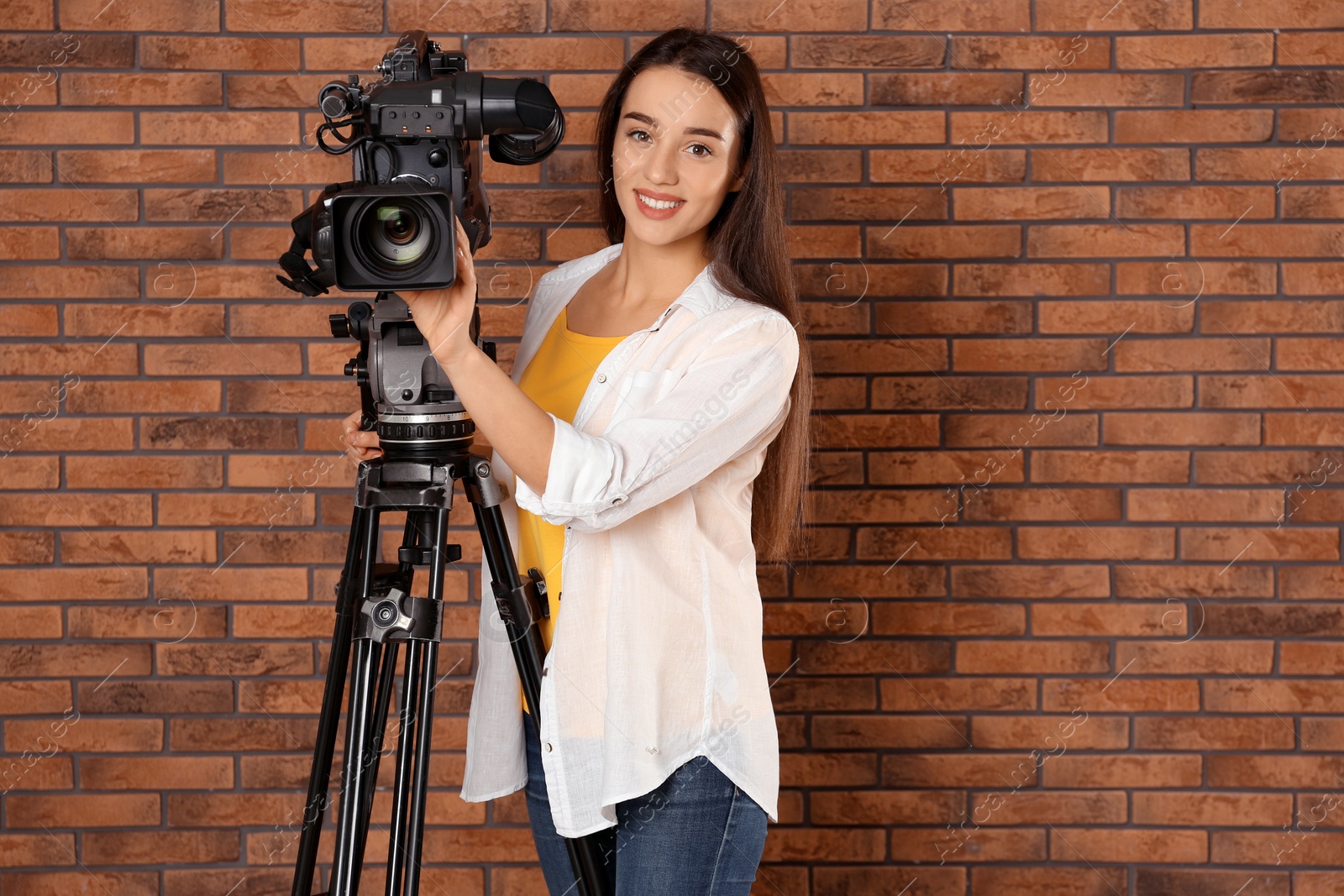 Photo of Operator with professional video camera near brick wall, space for text