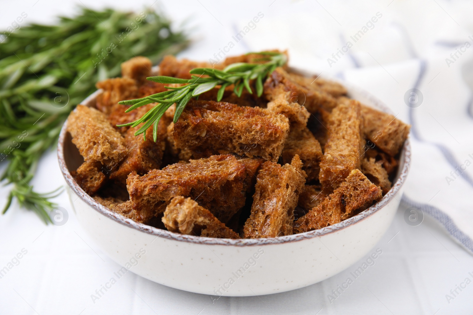 Photo of Crispy rusks with rosemary on white tiled table