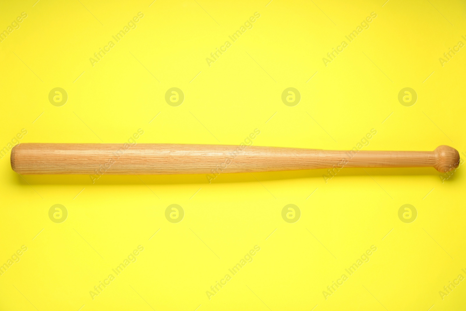 Photo of Wooden baseball bat on yellow background, top view. Sports equipment