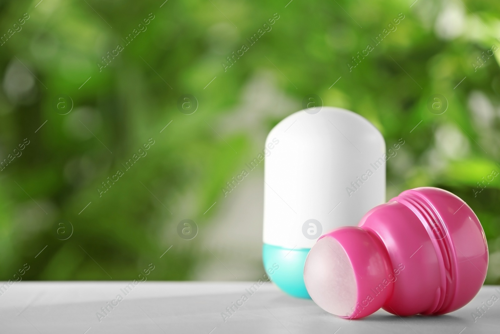 Photo of Different deodorants on white wooden table against blurred background. Space for text