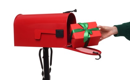 Photo of Woman putting Christmas gift into mailbox on white background, closeup. Sending present by mail