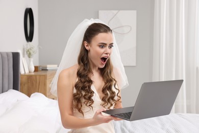 Photo of Shocked bride with laptop on bed in bedroom