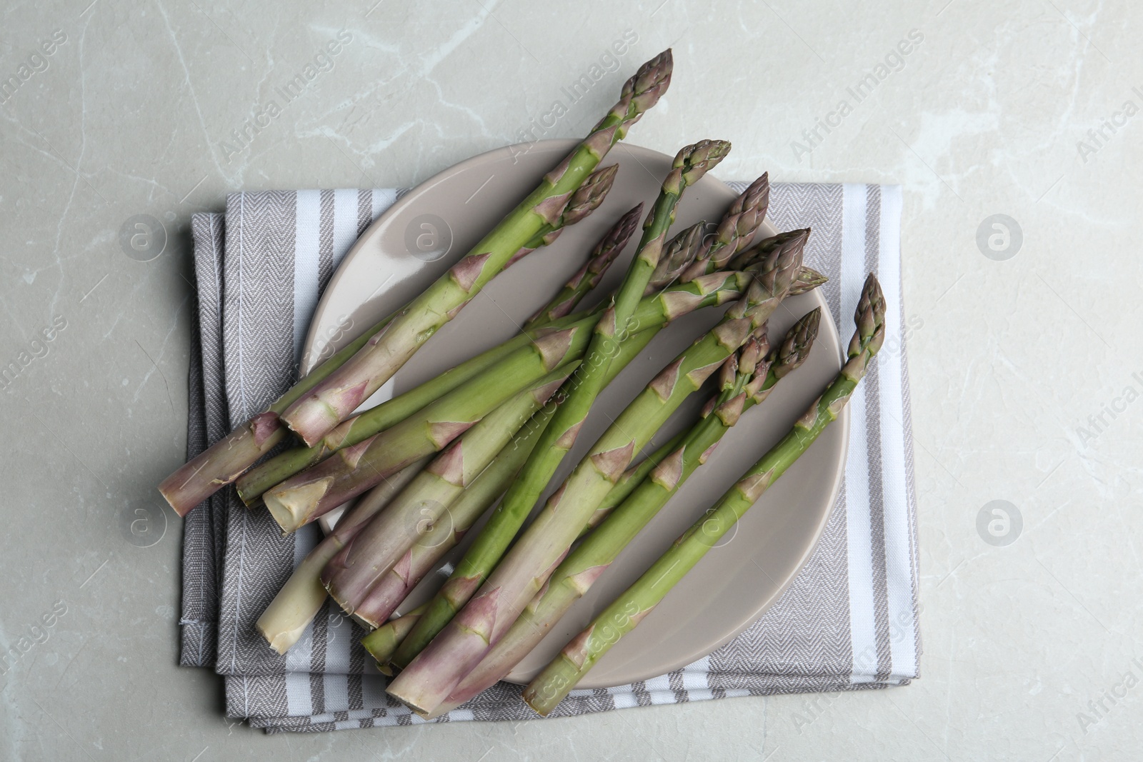 Photo of Fresh raw asparagus on light grey marble table, flat lay