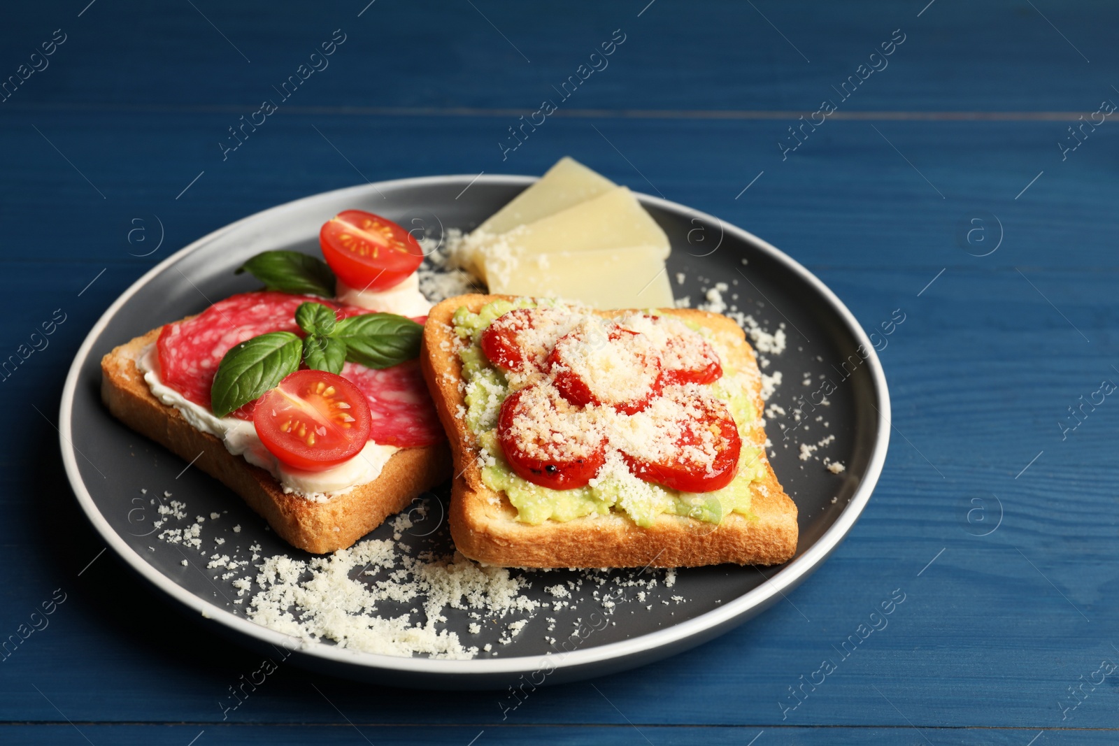 Photo of Tasty toasts with different toppings served on blue wooden table