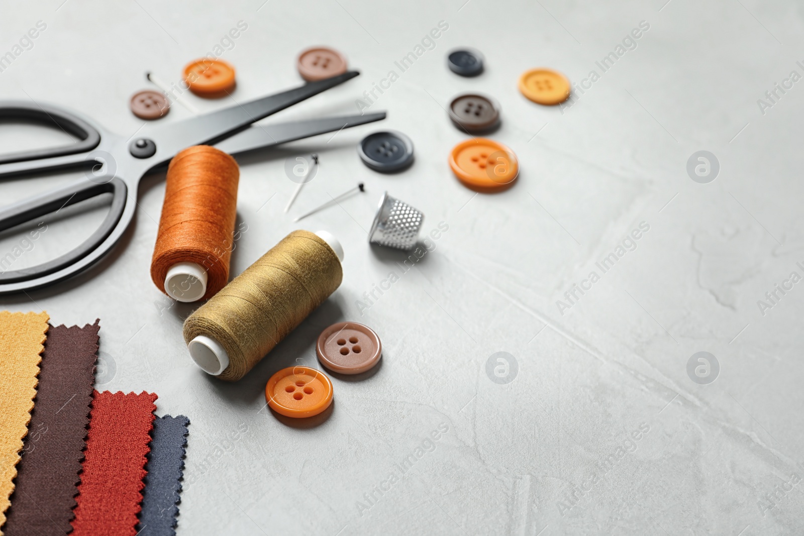 Photo of Set of tailoring accessories and fabric on light background