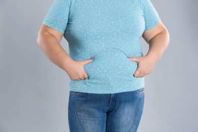 Overweight woman touching belly fat before weight loss on color background