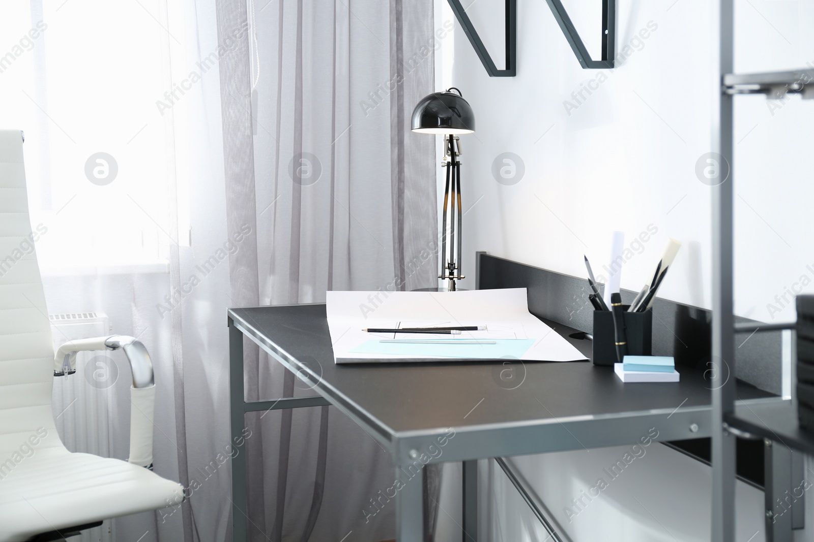 Photo of Stylish workplace with modern lamp and stationery