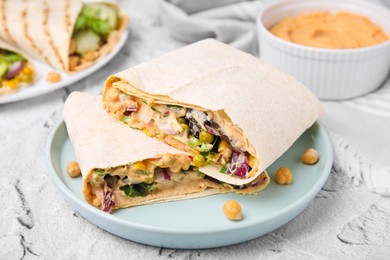 Photo of Delicious hummus wraps with vegetables on light grey textured table