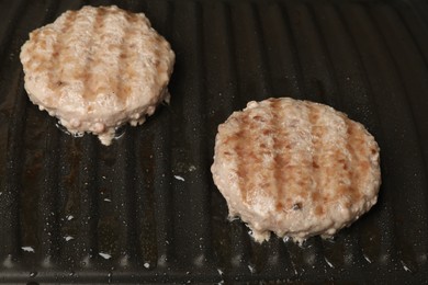Photo of Cooking tasty hamburger patties on grill pan, closeup
