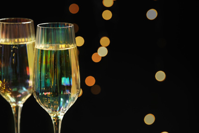 Photo of Glasses of champagne against blurred lights, closeup. Space for text